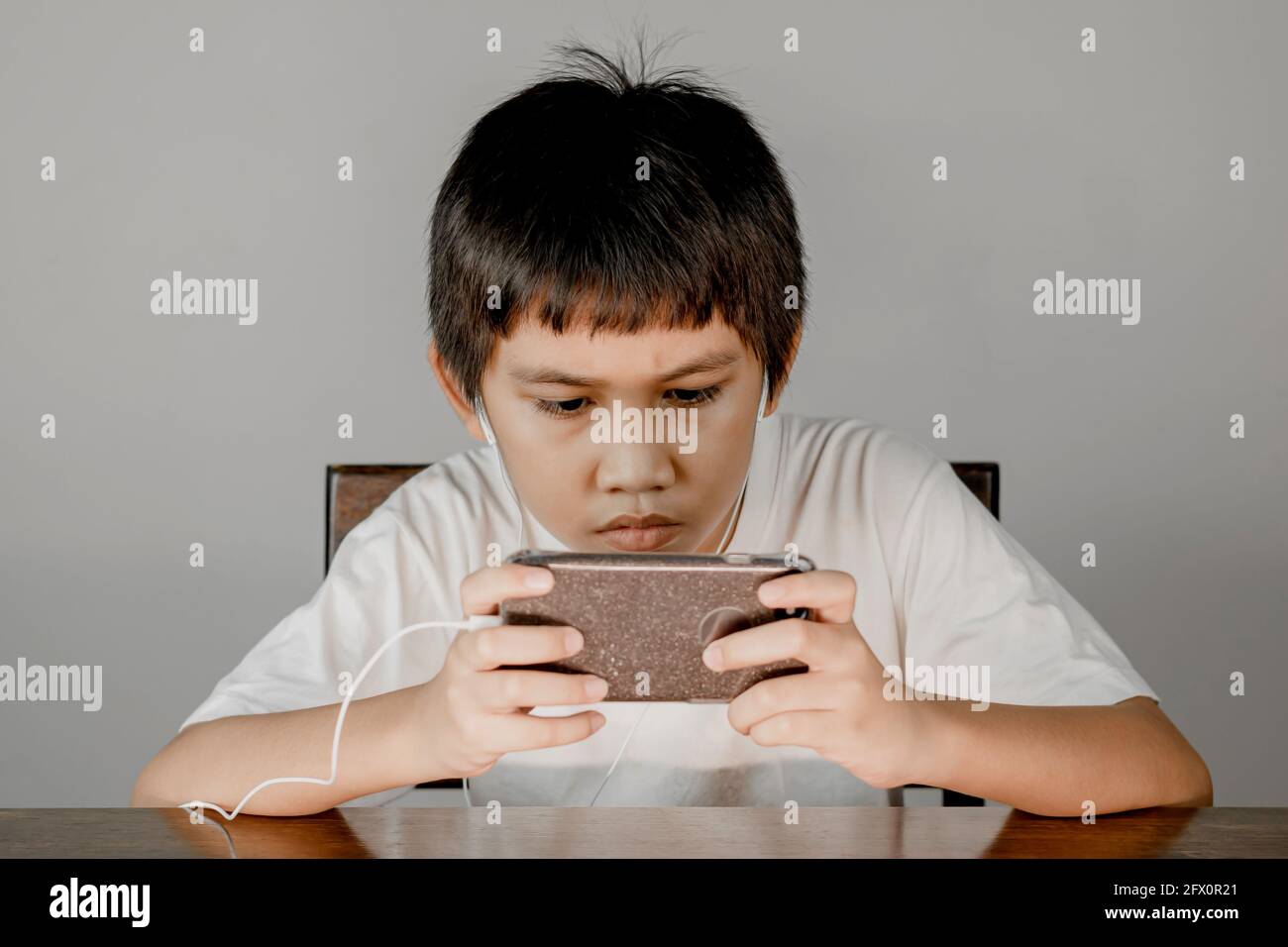 Gros plan sur le visage d'un garçon portant un casque et ayant l'intention de jouer à des jeux sur son smartphone. Banque D'Images Gros plan sur le visage d'un garçon portant un casque et ayant l'intention de jouer à des jeux sur son smartphone. Banque D'Images
