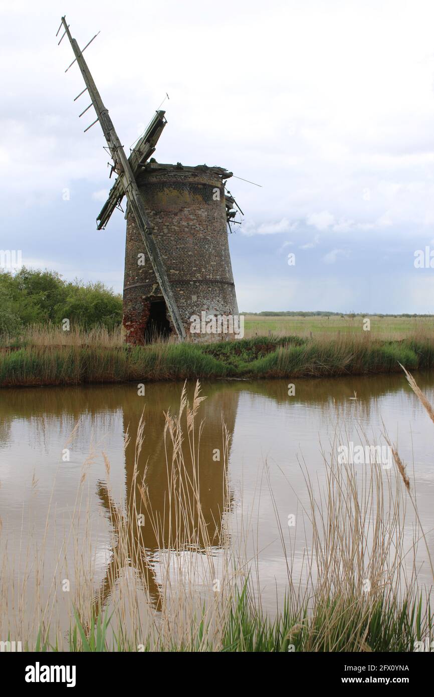 Paysage de l'ancien moulin à vent de brique pompe des voiles de bois se reflètent Dans l'eau de la rivière de Norfolk Broads à Horsey East Anglia Angleterre royaume-uni sur la banque de roseau Spring Banque D'Images