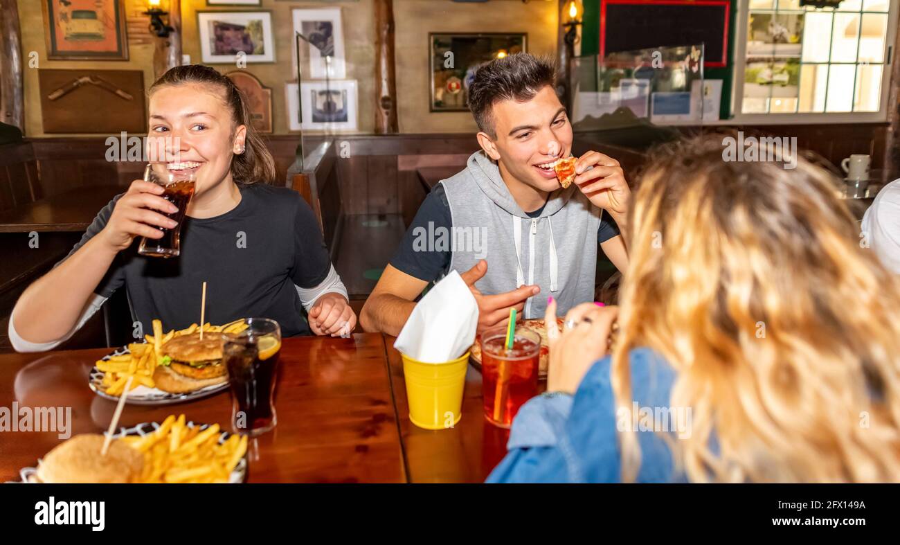 Groupe d'amis de la génération du millénaire qui mangent à la restauration rapide à l'intérieur dans le restaurant de pub irlandais. Des gens heureux qui font la fête et mangent ensemble. Jeunes adolescents actifs Banque D'Images