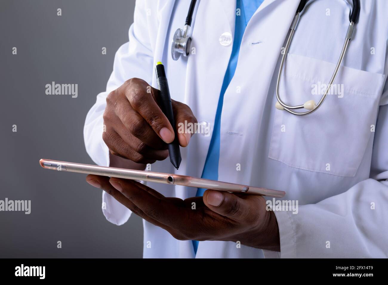 Section moyenne d'un médecin afro-américain utilisant une tablette graphique sur fond gris Banque D'Images