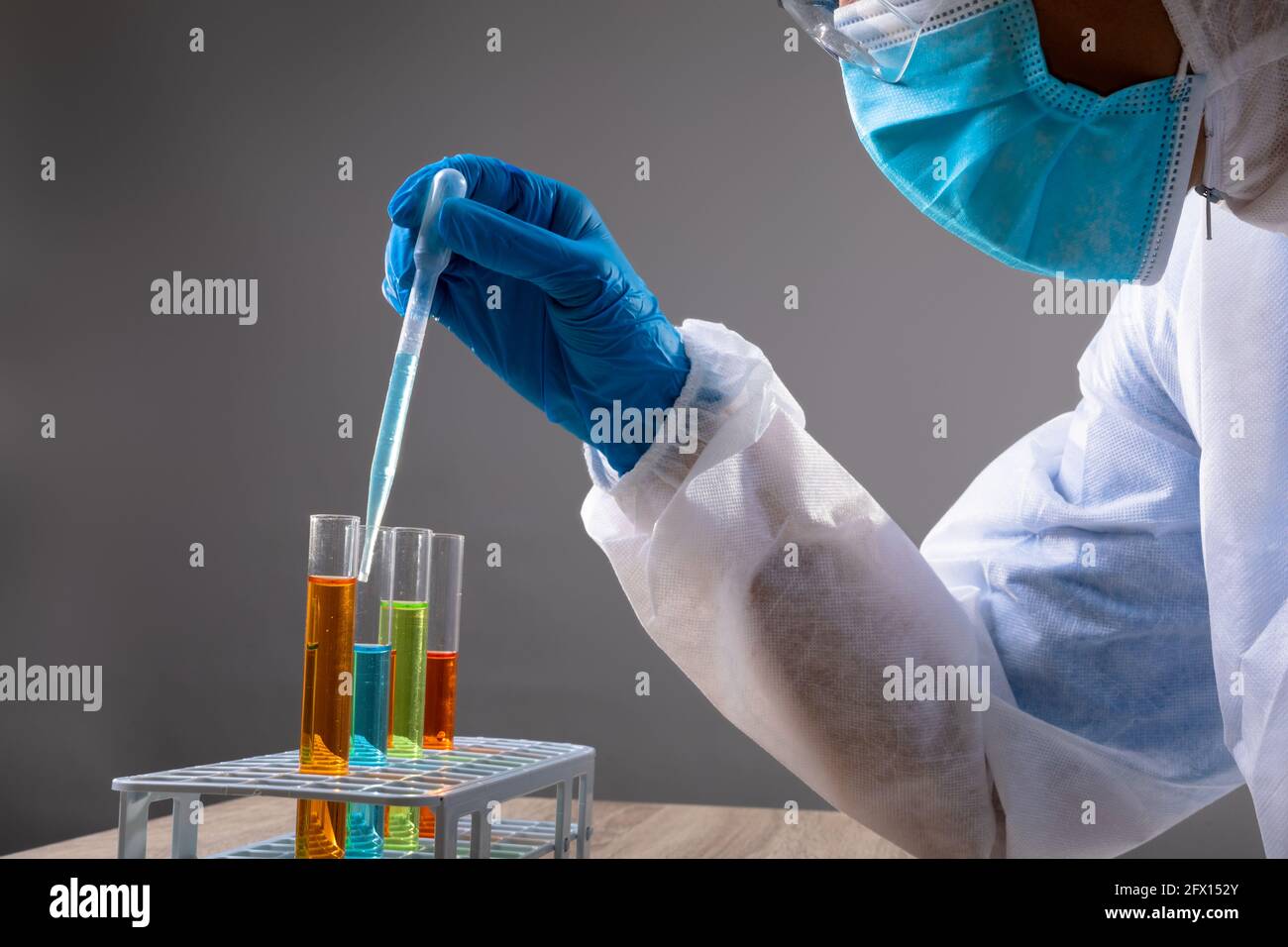 Section médiane de l'agent de santé portant un masque facial avec lequel travailler produits chimiques dans les tubes à essai Banque D'Images