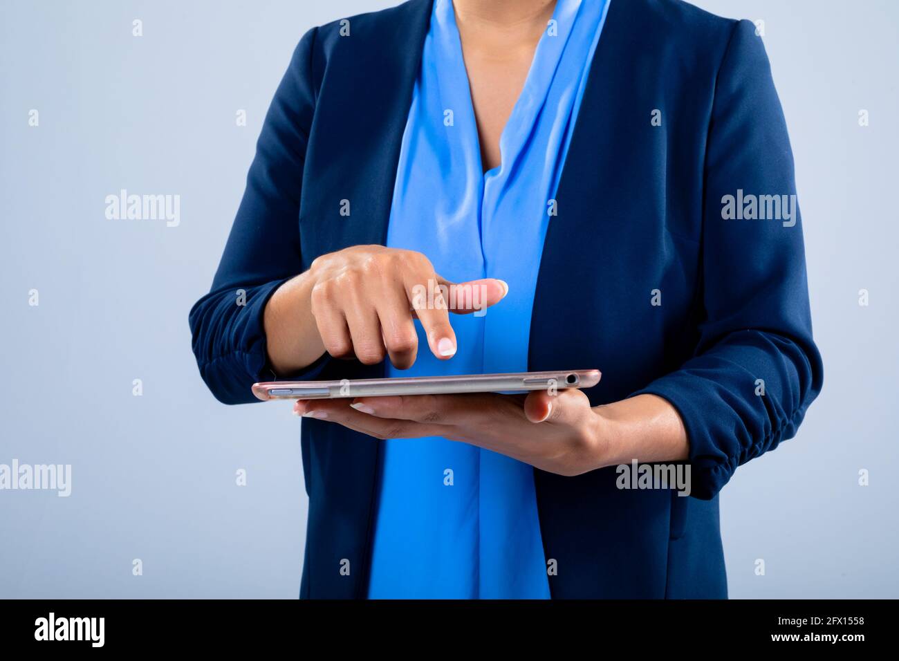 Section moyenne d'une femme d'affaires utilisant une tablette numérique contre le gris arrière-plan Banque D'Images