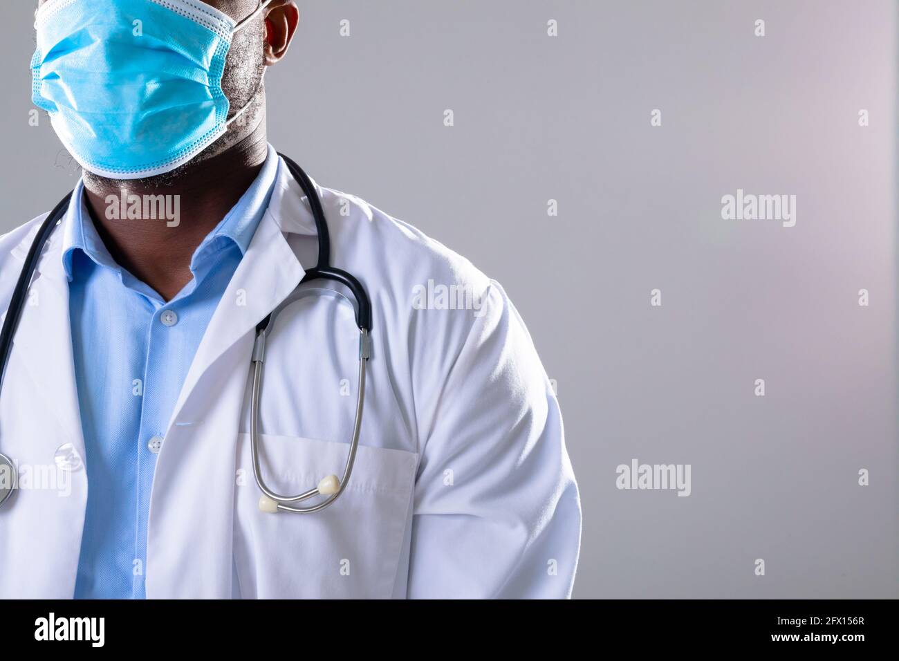 Section moyenne d'afro-américain médecin portant un masque facial sur fond gris Banque D'Images