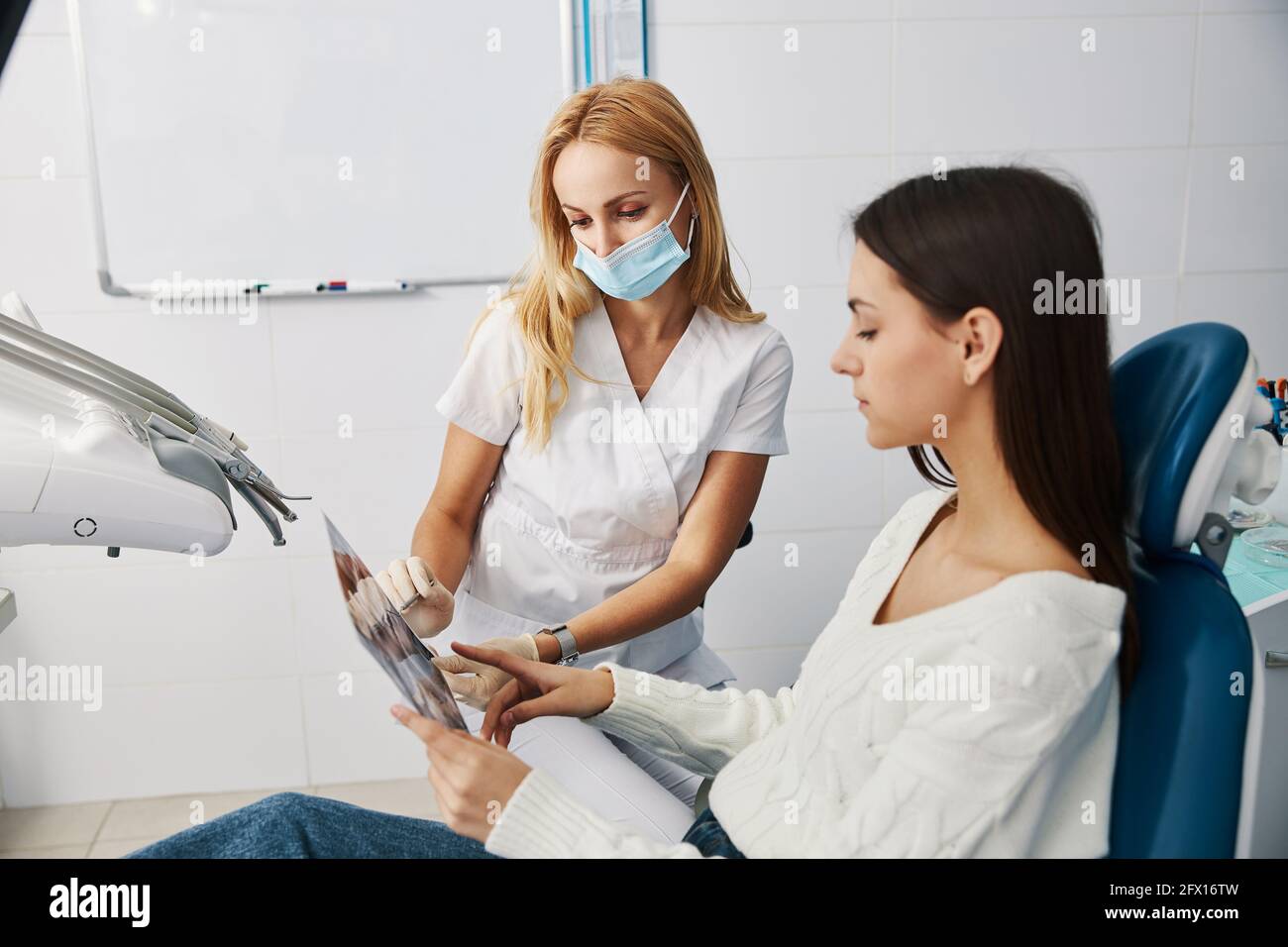 Chirurgien dentaire pointant avec l'explorateur sur les dents de rayons X. Banque D'Images