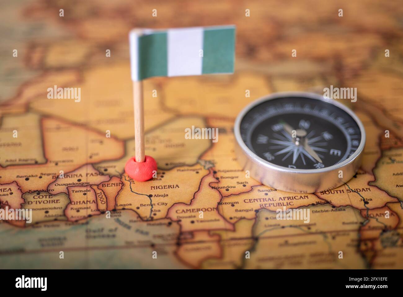Drapeau du Nigeria et boussole sur la carte du monde. Le concept de voyage et de tourisme. Banque D'Images
