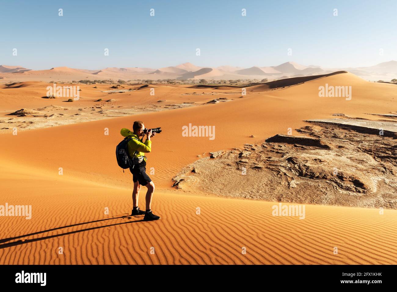 Photographe prenant des photos à Deadvlei, Namib-Naukluft National Park, Namibie, Afrique. Terrain séché avec du sable dans le désert du Namib au coucher du soleil. Photographie de paysage Banque D'Images