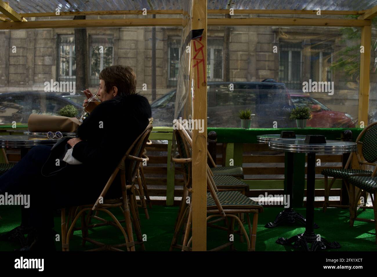 Une parisienne s'assoit seule, prenant un verre sur la terrasse temporaire d'un café à Paris après la levée des restrictions Covid-19 en 2021 - le Montmartre café, rue Custine, 75018, Paris, France Banque D'Images