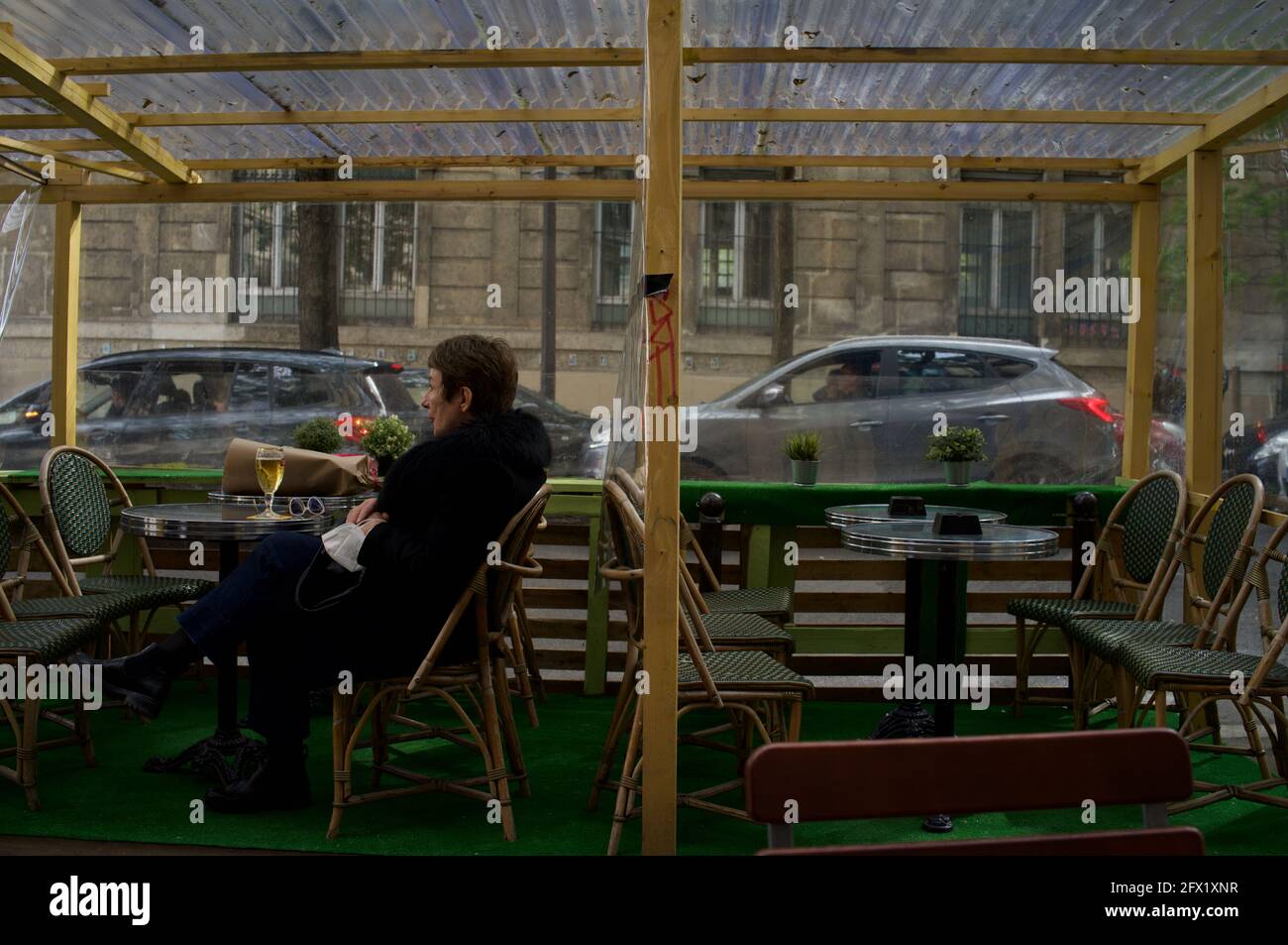 Une parisienne prend un verre le soir sur une terrasse temporaire du café de Paris, construite pour permettre aux clients de boire dehors après la levée des restrictions Covid-19 - le Montmartre café, rue Custine, 75018, Paris, France Banque D'Images