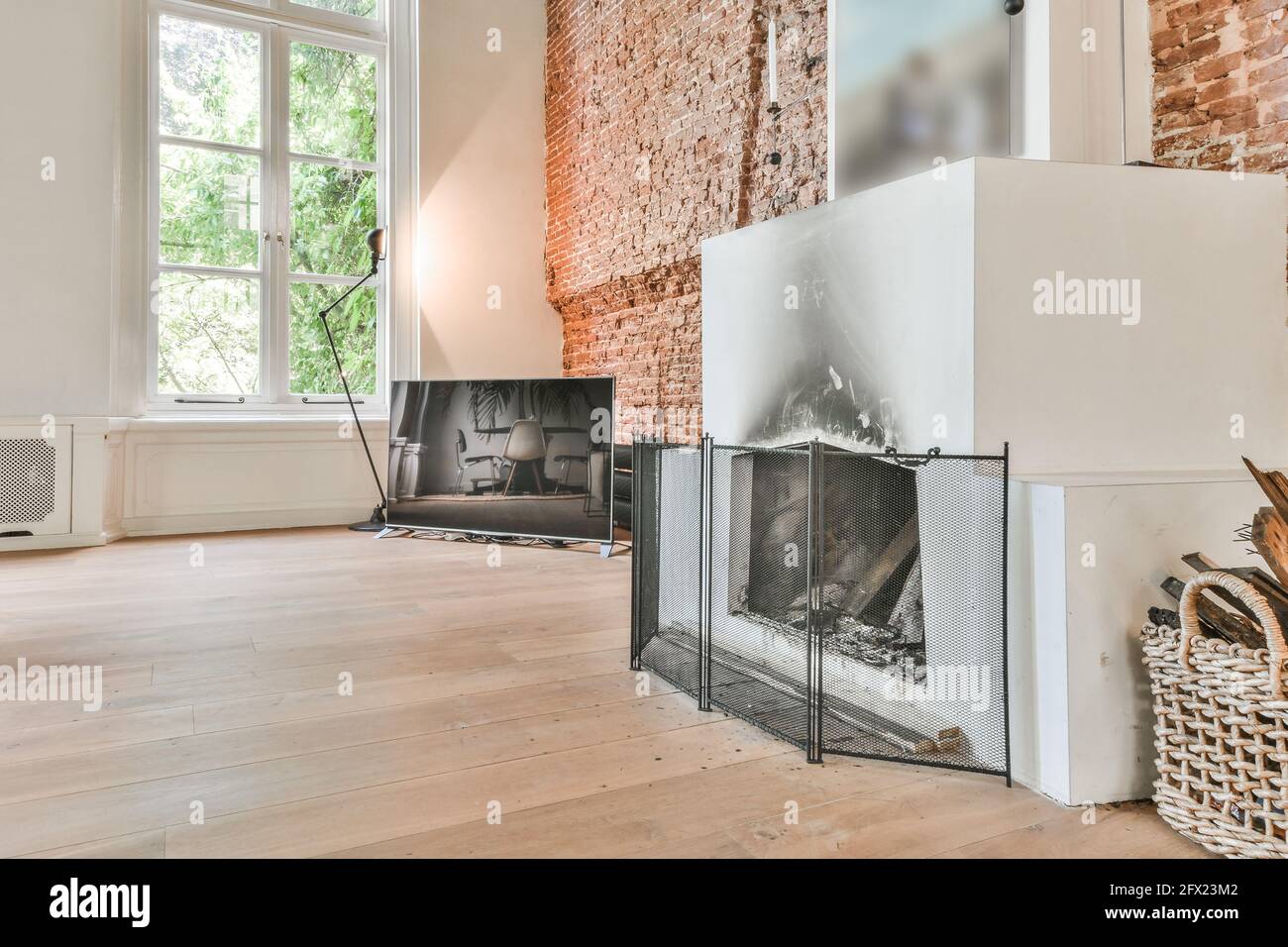 Salon Mansion avec cheminée blanche et TV sur bois sol contre mur de briques dans le style loft Banque D'Images