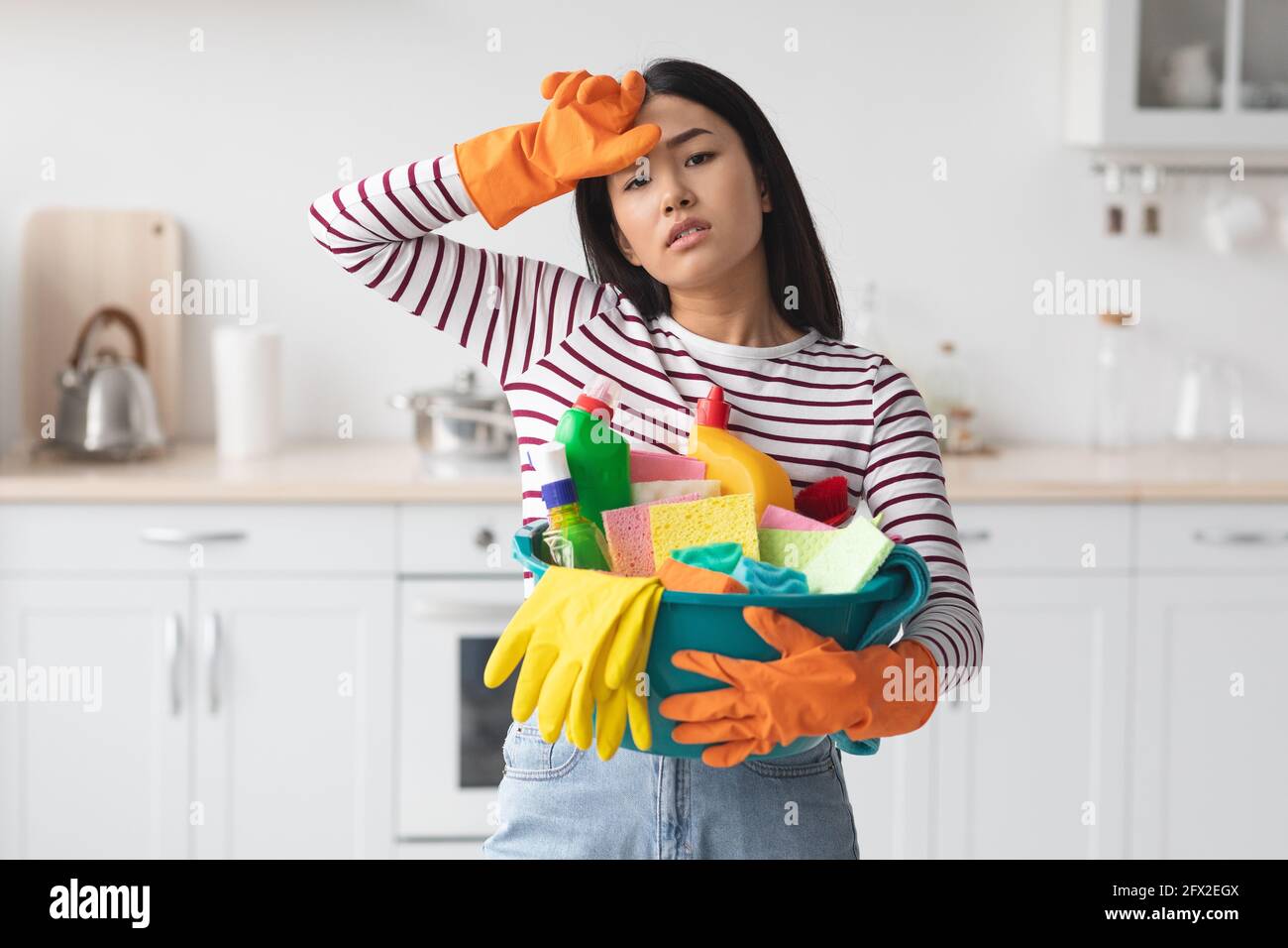 Femme asiatique travaillant dur avec busket plein de fournitures de nettoyage Banque D'Images