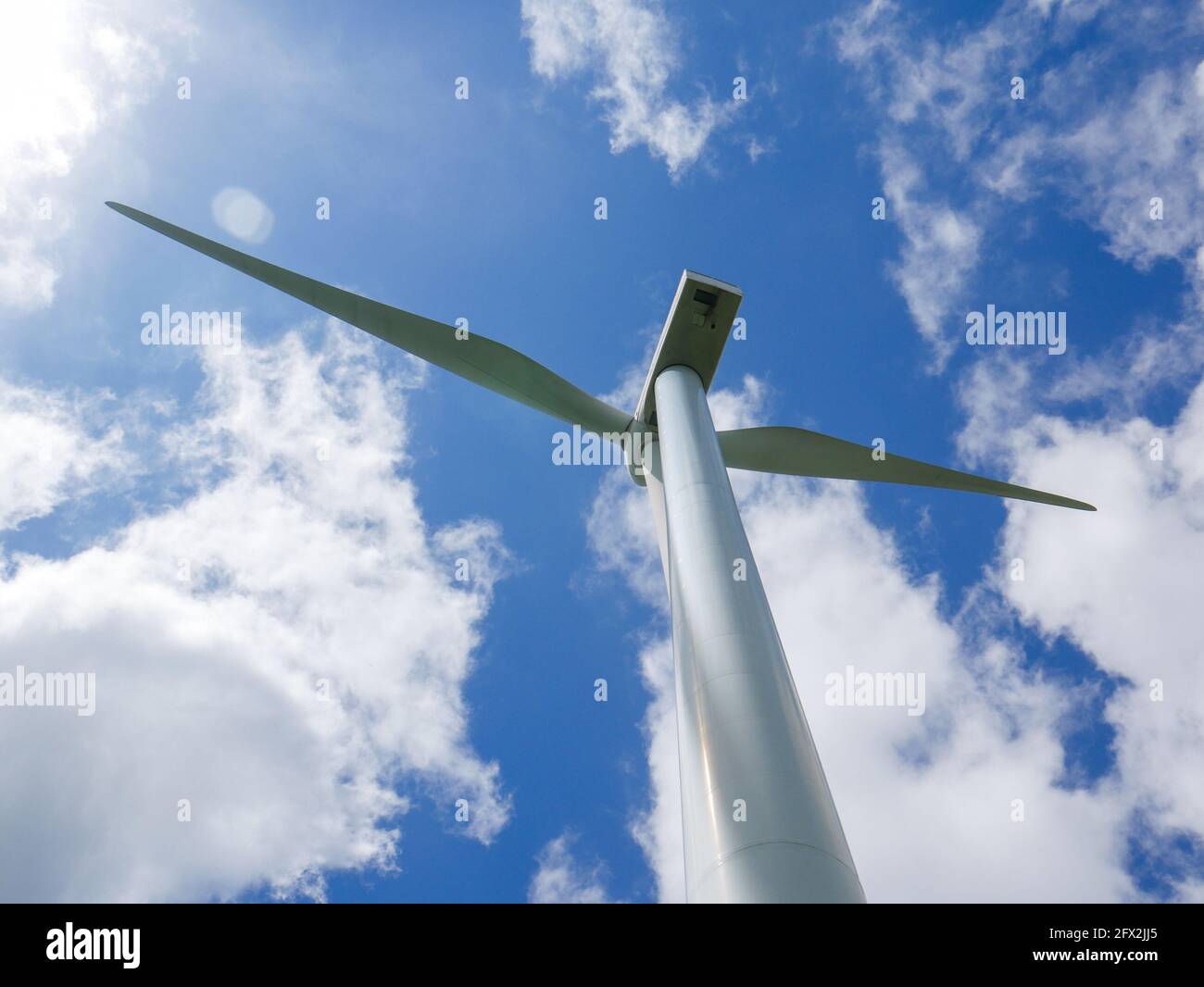 Éoliennes sur le terrain vert et vallonné avec le ciel bleu vif. Banque D'Images