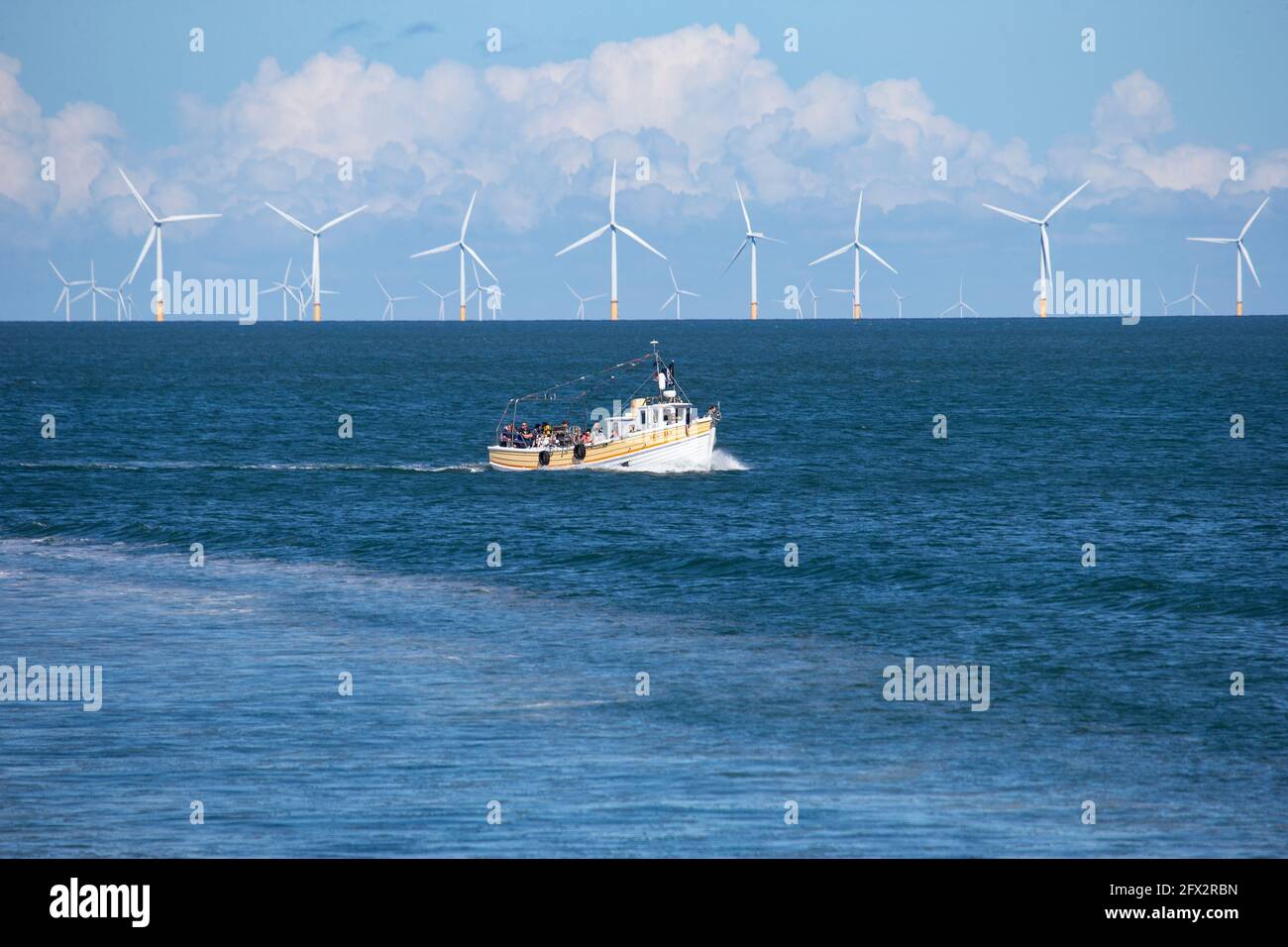 Bateau de plaisance Sea Jay avec des touristes sur une croisière de plaisir dans la baie de Llandudno, au nord du pays de Galles avec des éoliennes en arrière-plan Banque D'Images