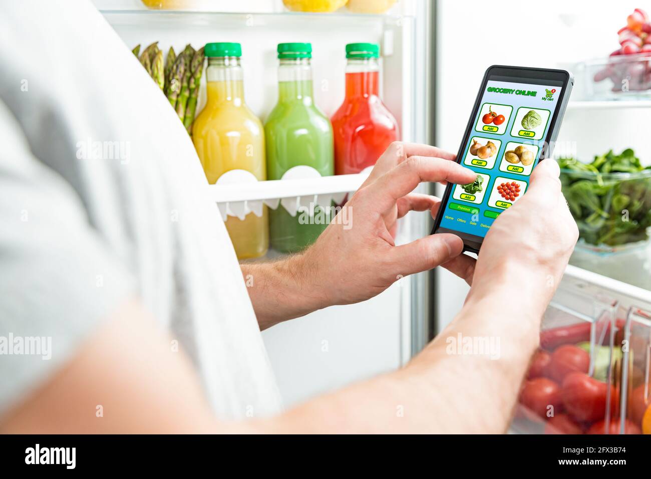 Homme utilisant un smartphone, achetant de la nourriture. Gros plan avec le téléphone. Courses en ligne. Application mobile de la boutique de produits alimentaires en ligne. Légumes frais au réfrigérateur Banque D'Images