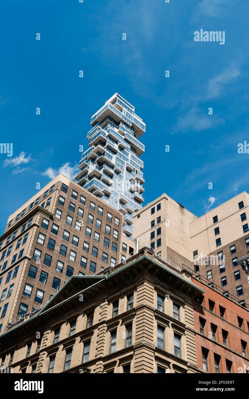 New York City, Etats-Unis - 25 juin 2018: Nouveau bâtiment d'appartements de luxe émergeant de derrière d'anciens bâtiments à Tribeca. Vue à angle bas pour un ciel bleu. Verti Banque D'Images