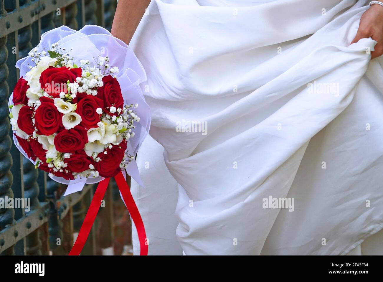 Image d'un bouquet de roses rouges dans la main de la mariée Banque D'Images