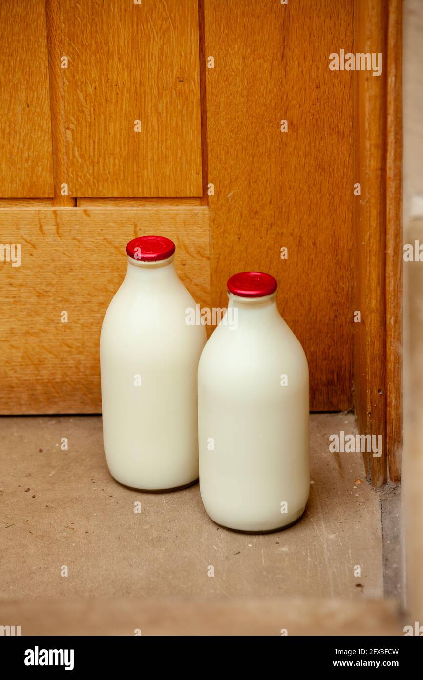 Deux pintes de lait frais dans des biberons traditionnels en verre à une porte Banque D'Images