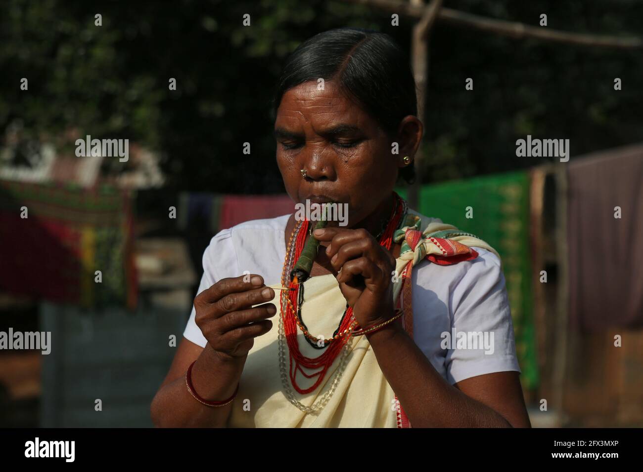 LANJIA SAORA TRIBE - Tribal femme fumant pipe de pulam fait de feuilles. Bouchons ronds en bois ou taitalya dans les oreilles et bijoux Khagla et Jatong autour d'elle Banque D'Images