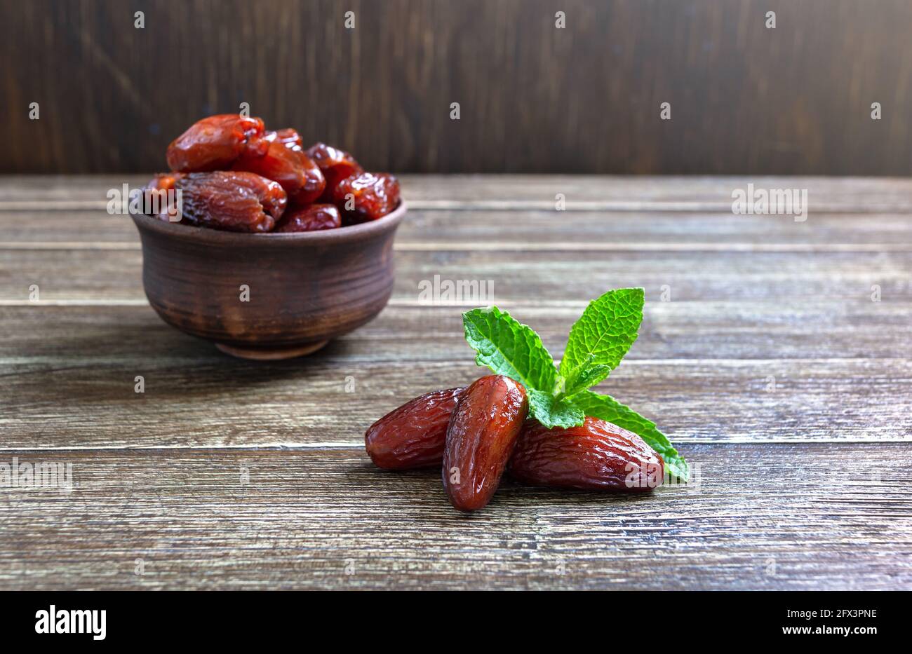 Les fruits et les feuilles de menthe fraîche séchés au soleil sont dans un bol en céramique sur une table en bois. Fruits secs biologiques. Banque D'Images