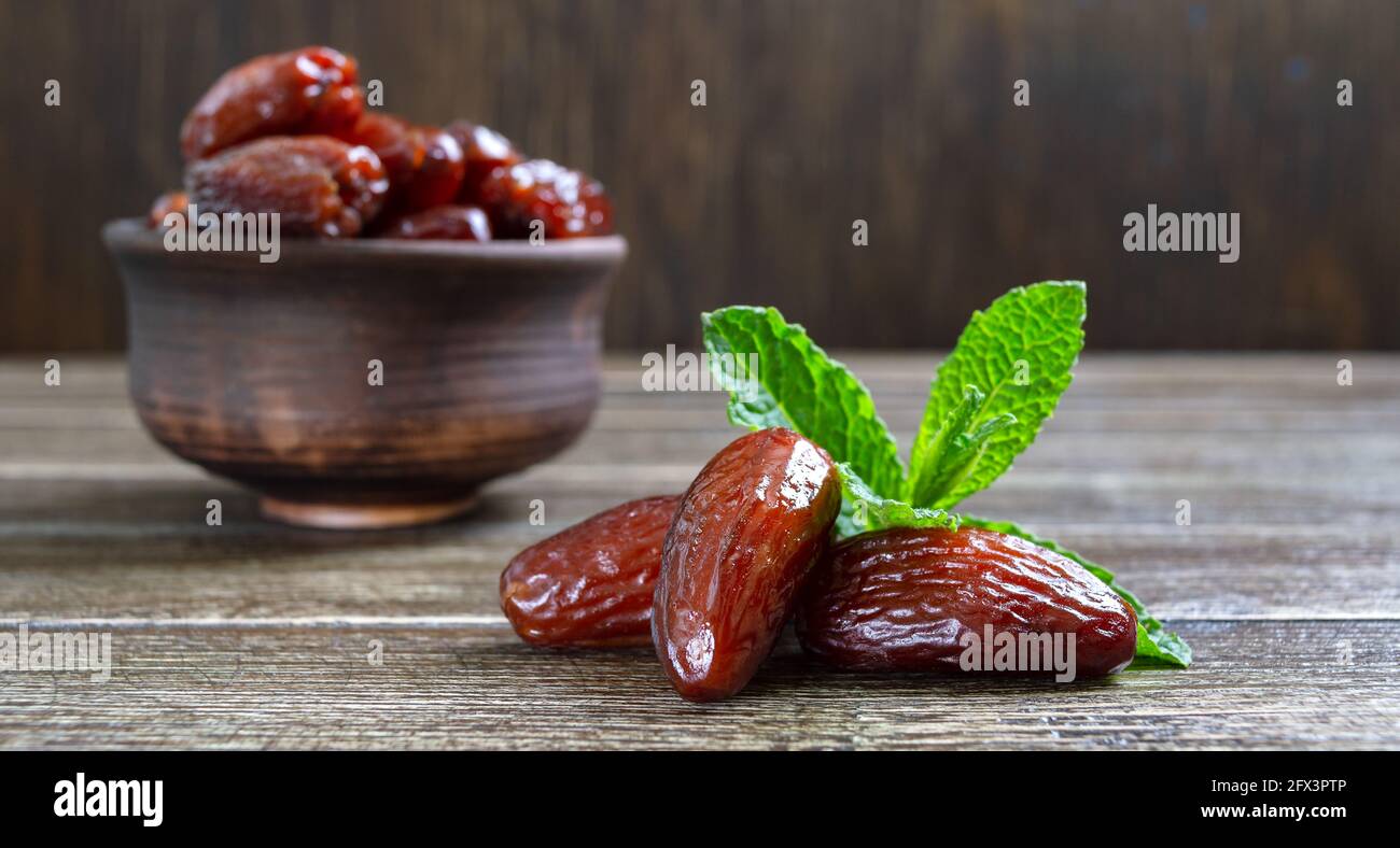 Les fruits et les feuilles de menthe fraîche séchés au soleil sont dans un bol en céramique sur une table en bois. Gros plan Banque D'Images