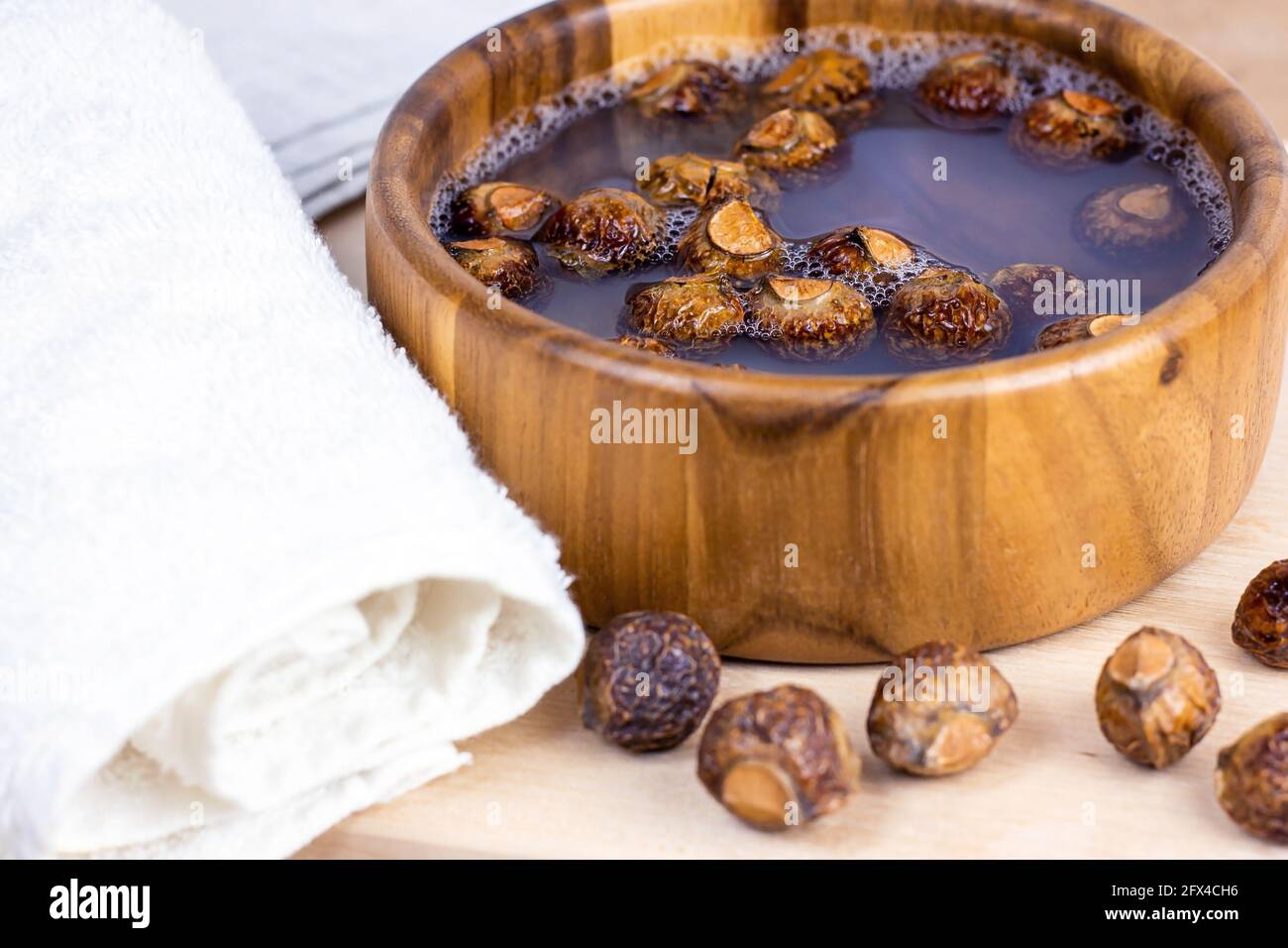 Faire dorer les noix de savon sec (Soapberries, Sapindus Mukorossi) dans l'eau avec la serviette pour le linge biologique et un soin doux et naturel de la peau sur fond clair Banque D'Images Faire dorer les noix de savon sec (Soapberries, Sapindus Mukorossi) dans l'eau avec la serviette pour le linge biologique et un soin doux et naturel de la peau sur fond clair Banque D'Images