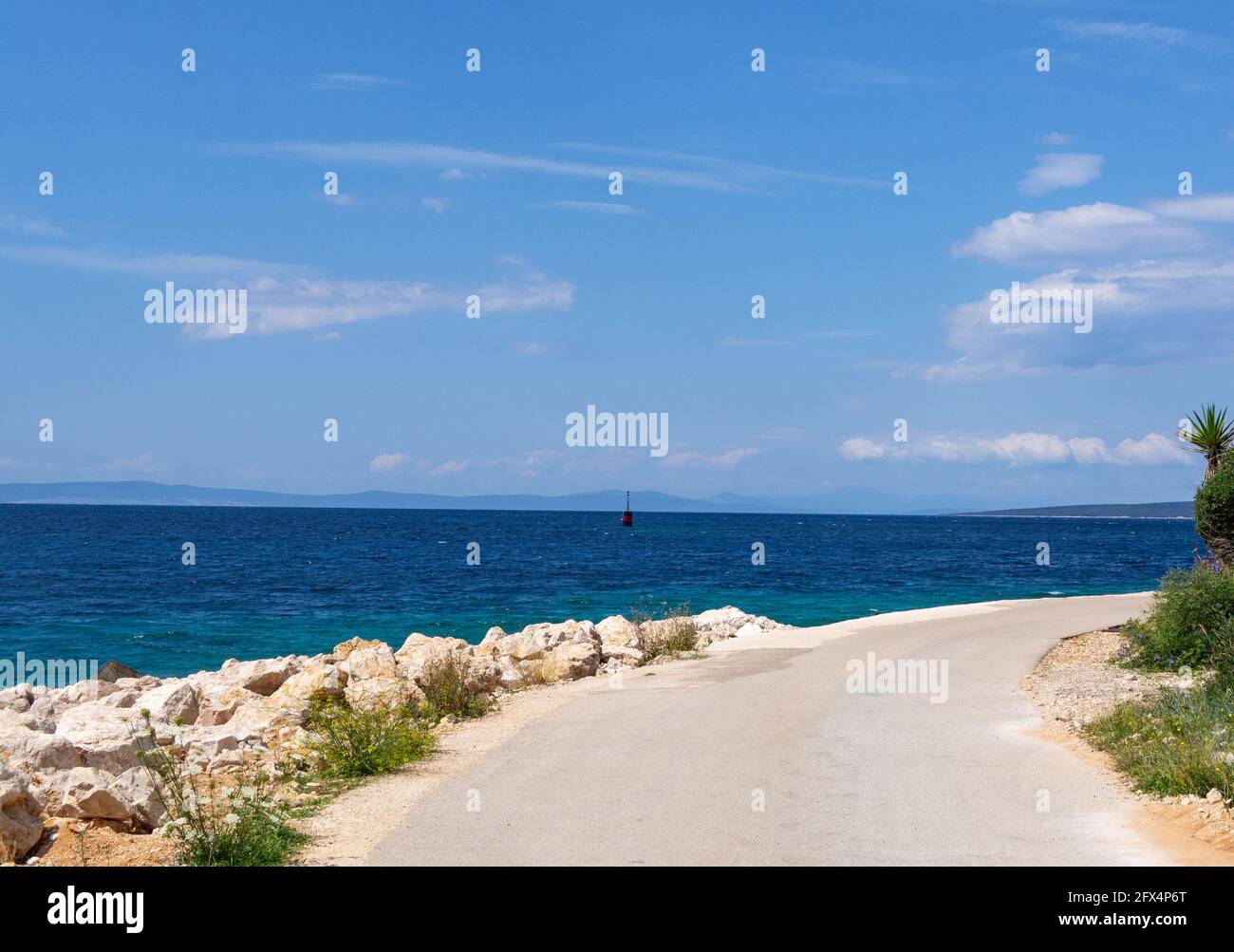 Croatie. L'île de Pag. Un virage routier sur la côte Adriatique. Été, mer d'azur, ciel bleu. Banque D'Images
