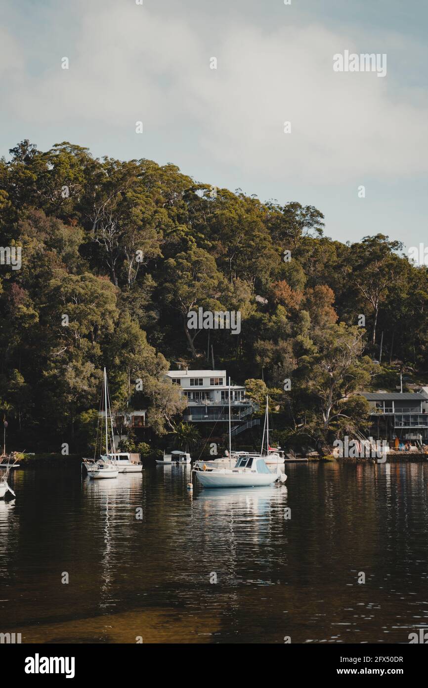 Bateaux sur l'eau devant des maisons idylliques en bord de mer à Berowra Waters, Nouvelle-Galles du Sud. Comme vu de la Great North Walk. Banque D'Images