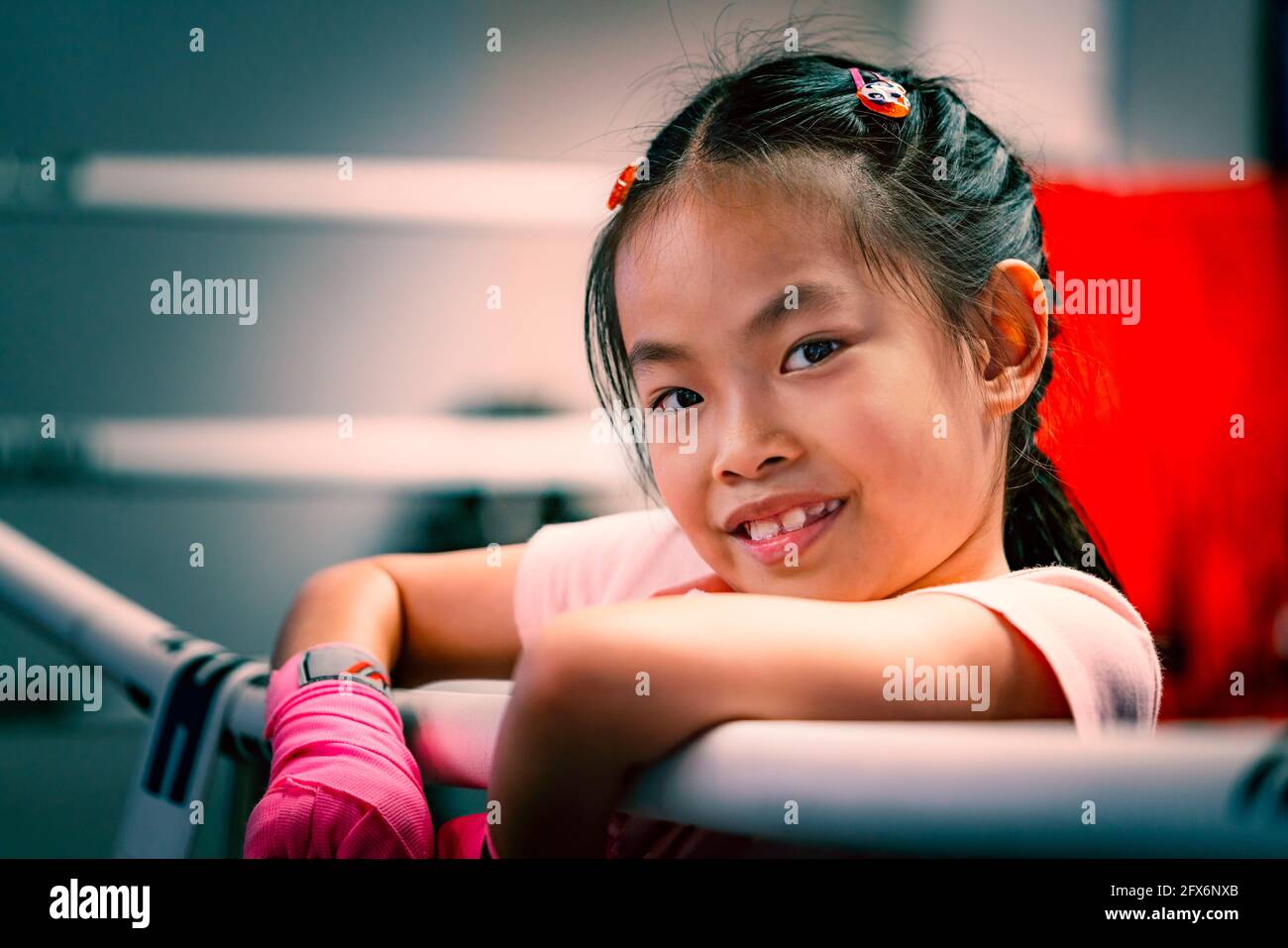Portrait d'une fille asiatique sur l'anneau de boxe, tenant la robe de l'anneau de boxe, gros plan sur le visage mignon avec le sourire, yeux regardant l'appareil photo, couleur ajustée. Enfant Banque D'Images