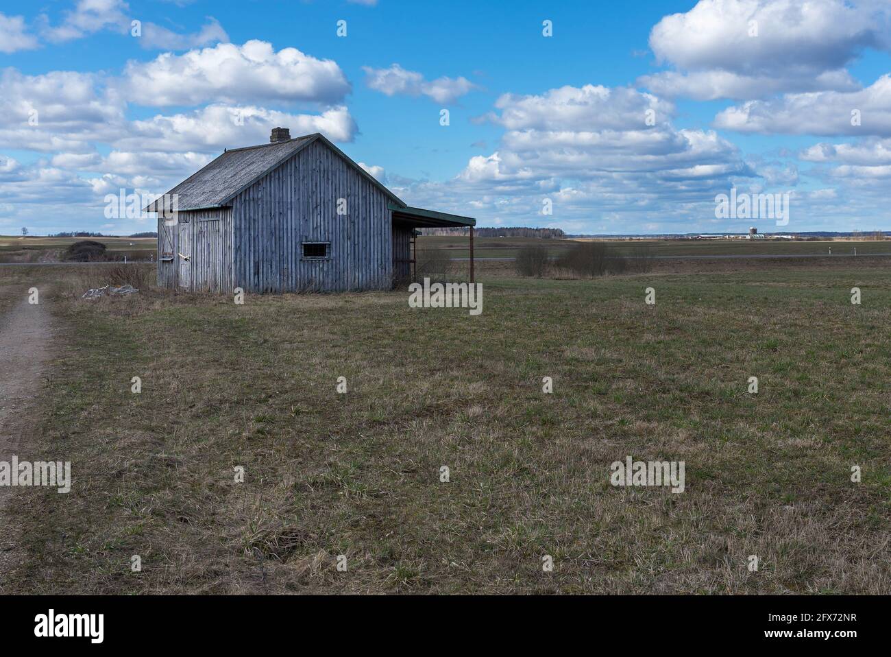 Une ancienne petite maison en bois abandonnée dans les champs ciel nuages, à côté d'une grange de chemin ou d'un concept effrayant. Banque D'Images