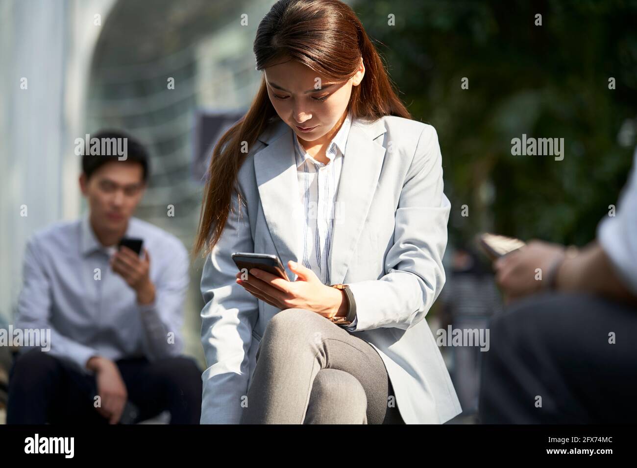 femme d'affaires asiatique regardant le téléphone mobile à l'extérieur Banque D'Images