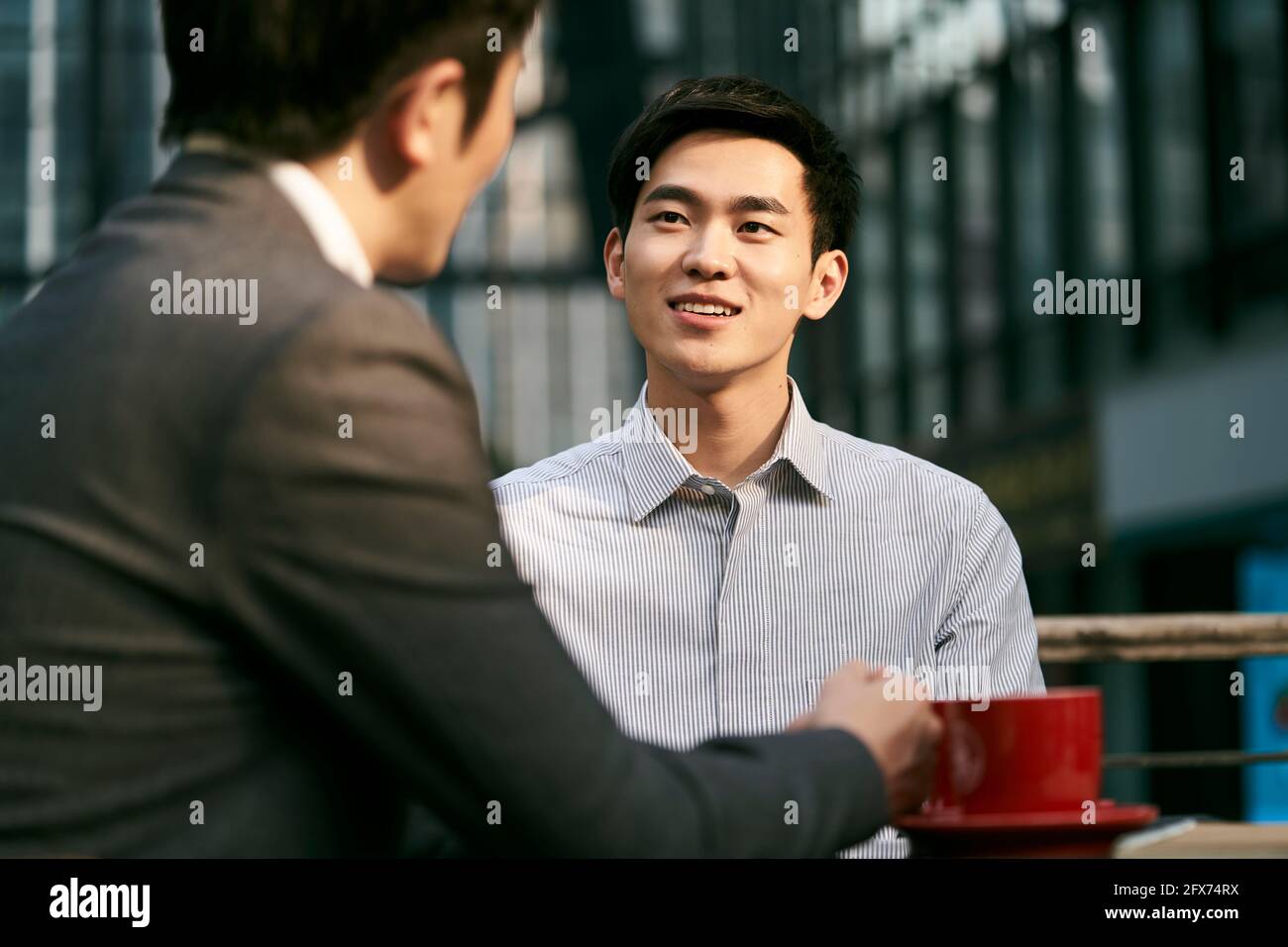 deux hommes d'affaires asiatiques discutent d'affaires lors d'un café en plein air boutique Banque D'Images
