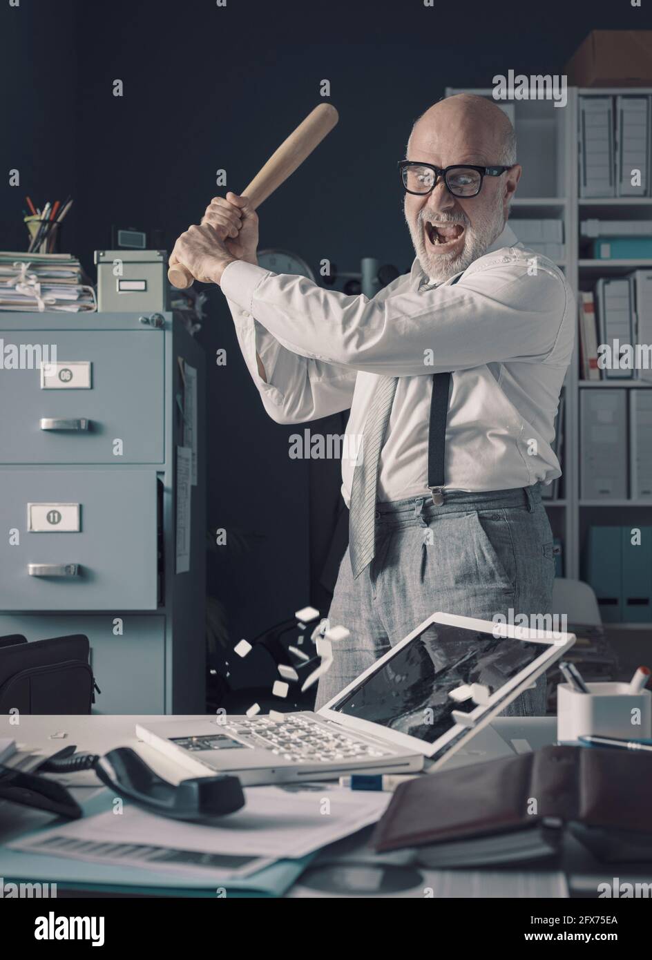 Un homme d'affaires fou stressé détruisant son bureau et son ordinateur portable avec une batte de baseball, le concept de l'épuisement professionnel Banque D'Images