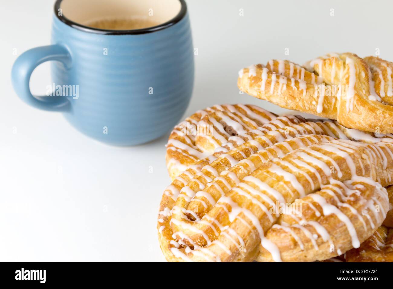 Un petit pain à la cannelle ou un petit pain à la cannelle sur l'assiette avec une tasse de café bleu. Boulangeries classiques américaines ou françaises. Banque D'Images