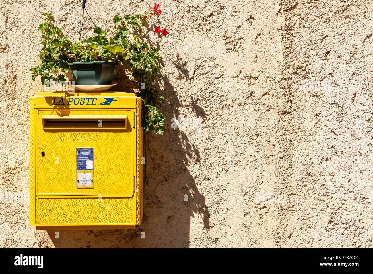 Boîte postale jaune la poste française, avec un pot de fleurs Banque D'Images