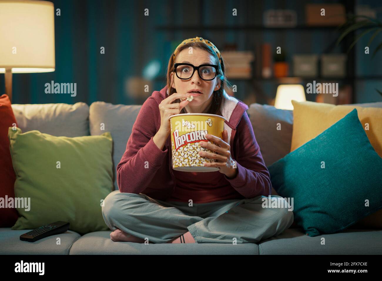 Femme regardant un film de suspense et mangeant du pop-corn Banque D'Images