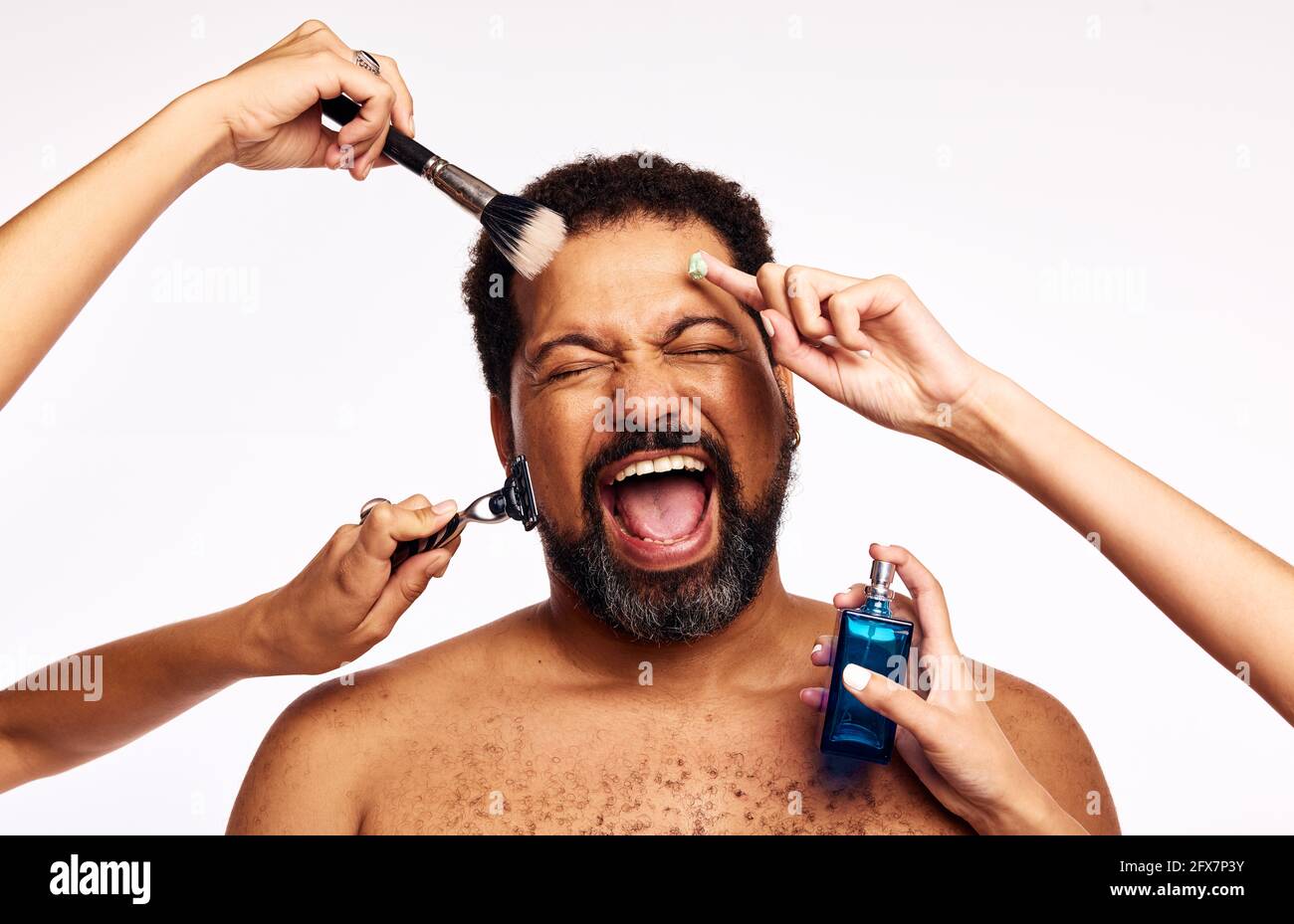 Mains de femmes se raser, appliquer le maquillage et le cologne à la personne barbu excitée. Homme criant avec joie tout en étant soigné par beaucoup de mains sur fond blanc Banque D'Images