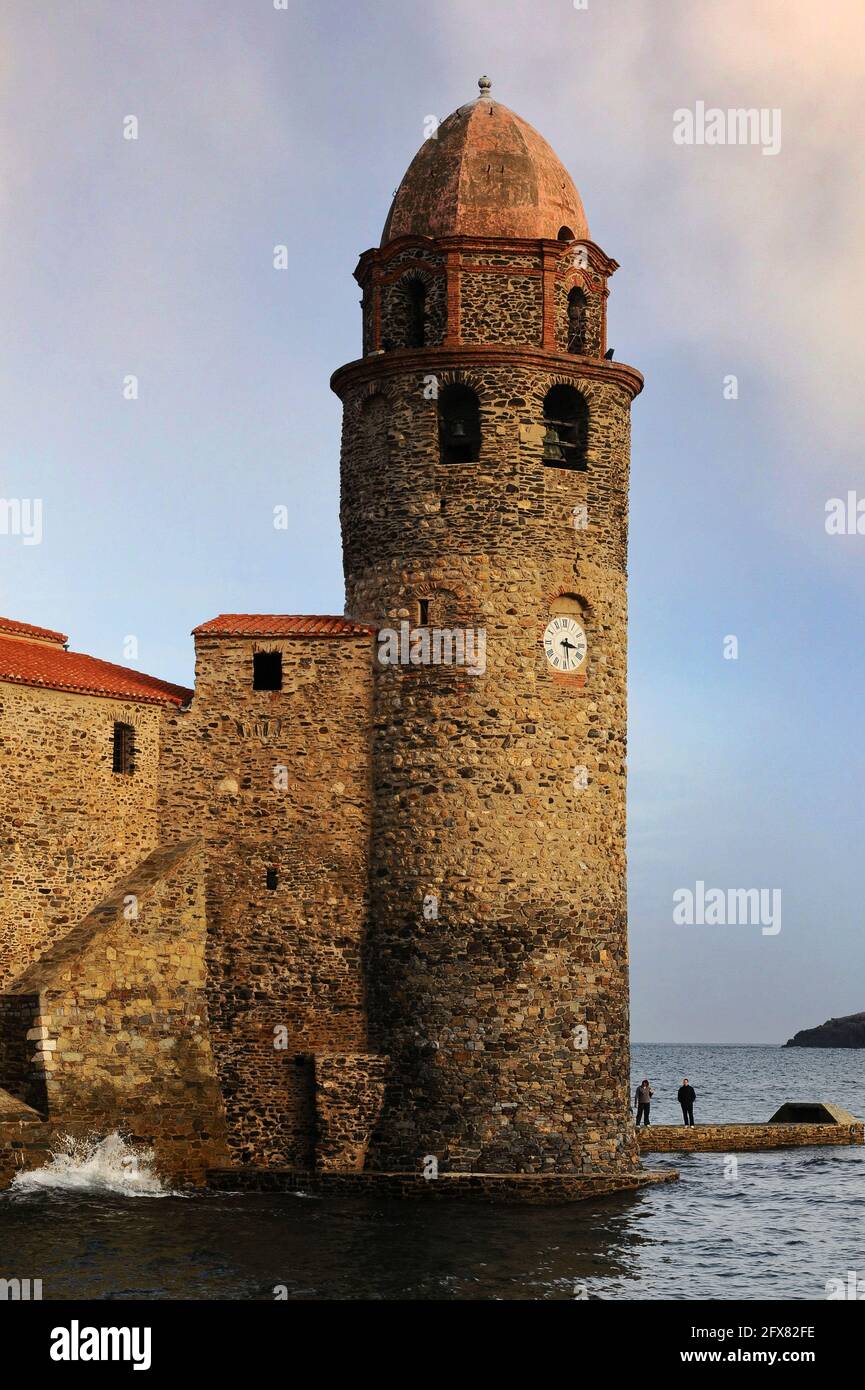 Église notre-Dame-des-Anges, Collioure, Pyrénées-Orientales, Occitanie, France. Le beffroi de l’église, aujourd’hui surmonté d’un dôme rose de style toscan, a été construit initialement comme un phare médiéval de pharos et a signalé l’emplacement de l’ancien port de commerce aux navires en mer avec de la fumée le jour et du feu la nuit. Le phare a été mis hors service en 1600s, lorsque Collioure a perdu sa fonction principale dans les eaux plus profondes de Port-Vendres, et en 1693, la tour a été transformée en clocher ou campanile. Banque D'Images