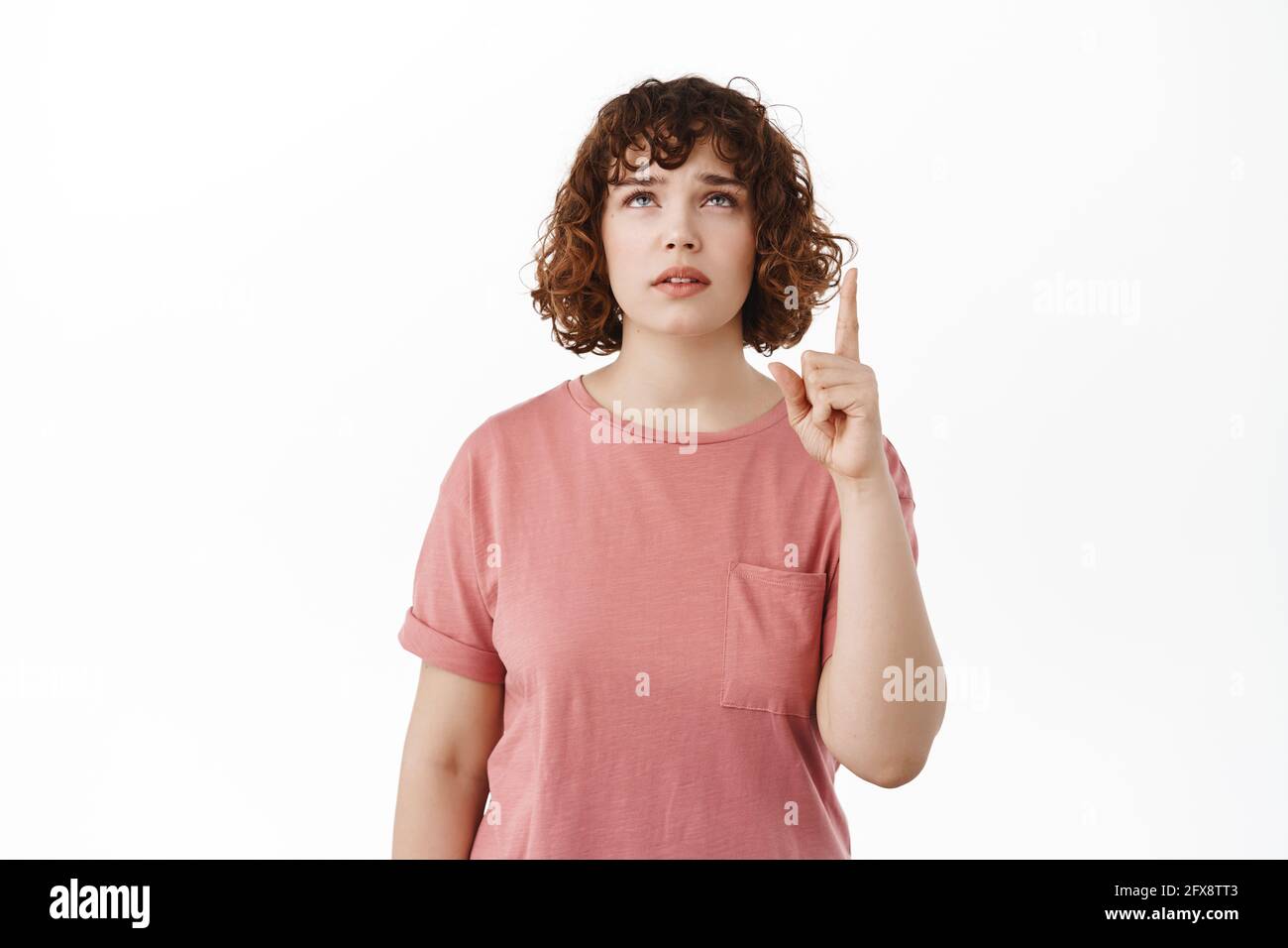 Une jeune femme qui levait les sourcils hésitait, pointant et regardant avec le visage douteux questionné, lisant la publicité sur le dessus, debout dans t Banque D'Images