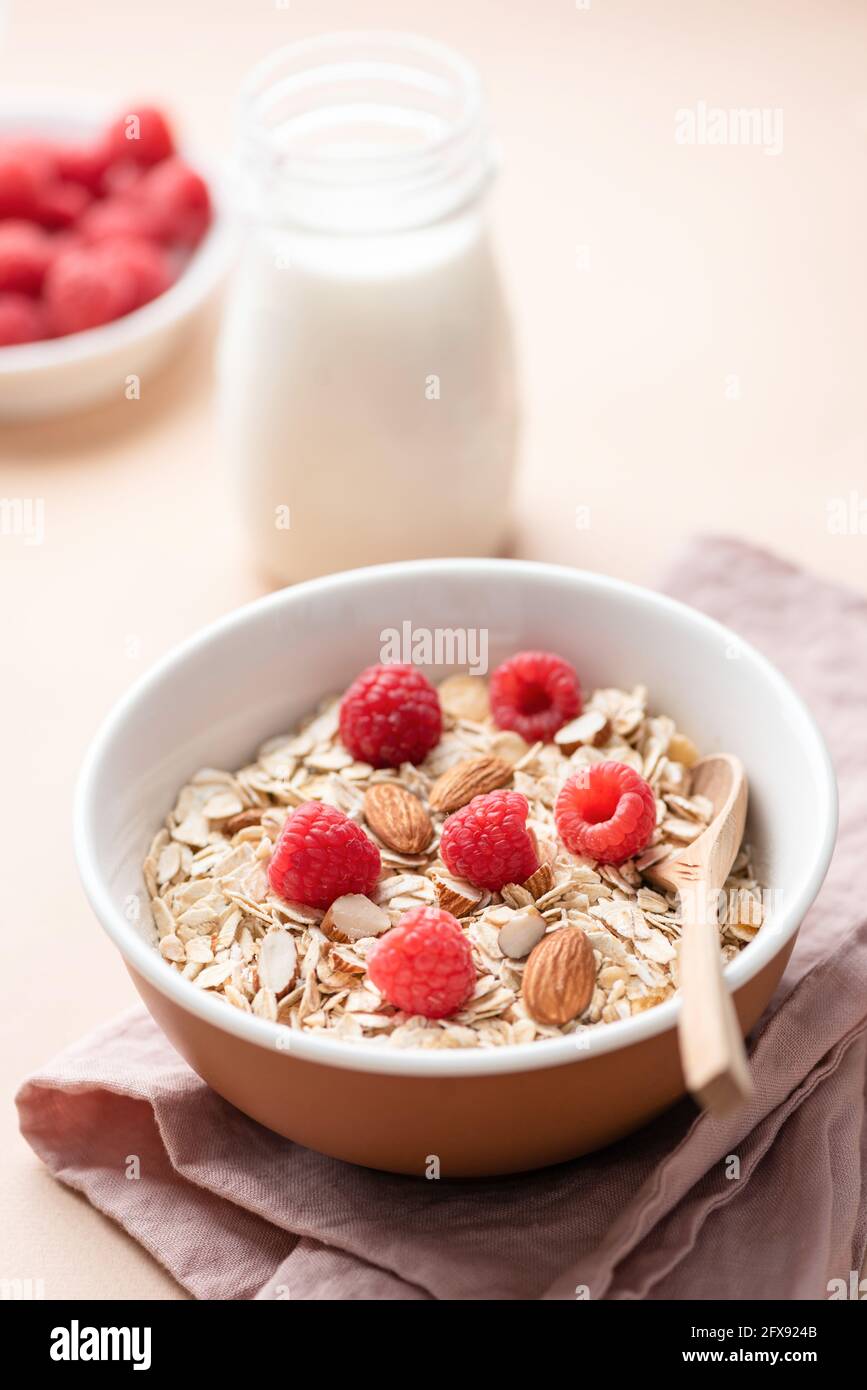 Dans un bol, faire sécher l'avoine, les muesli d'avoine avec les framboises et les noix d'amande. Aliments sains et nutritifs pour le petit déjeuner. Régime, concept de perte de poids Banque D'Images