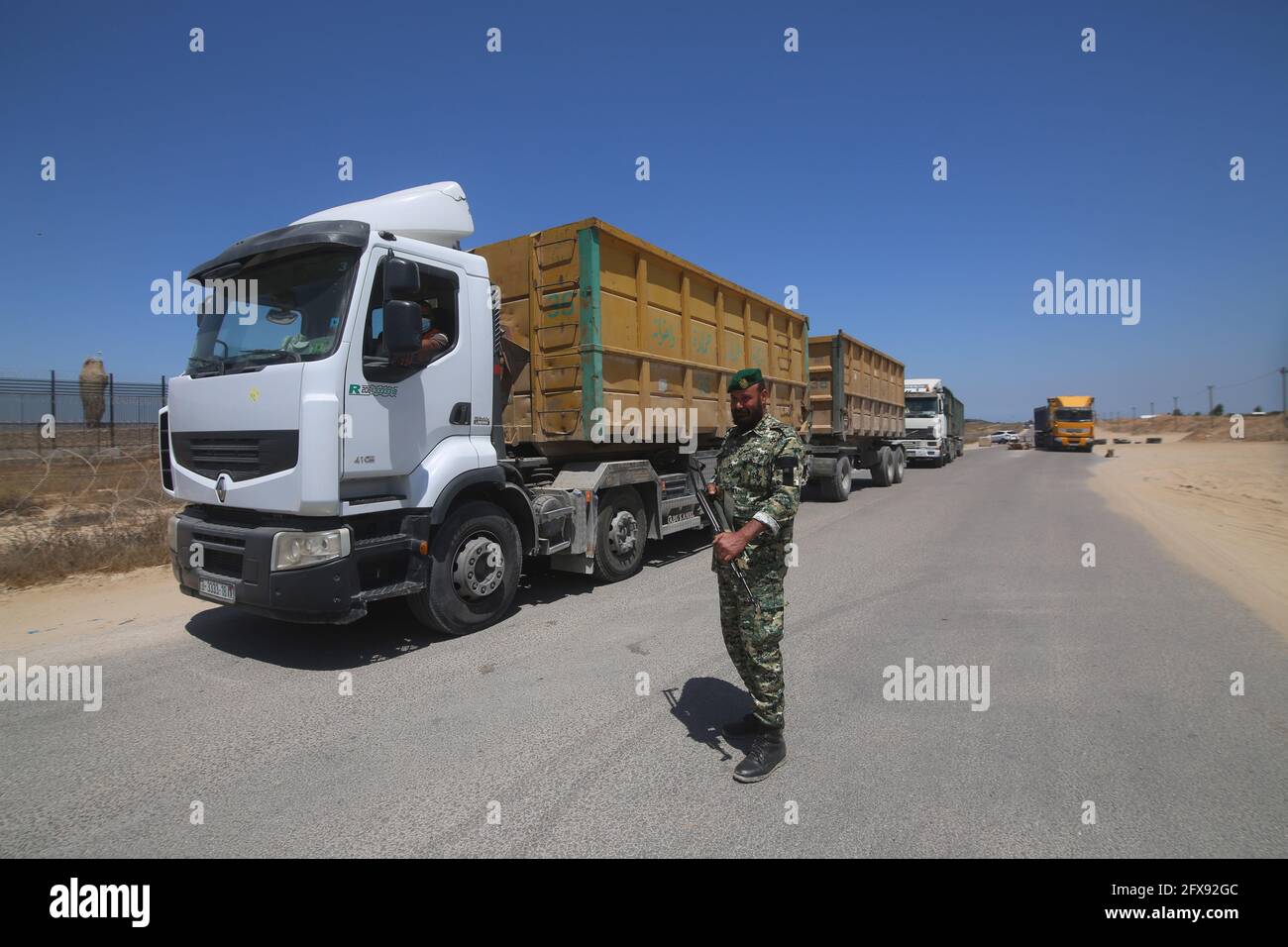 Rafah. 25 mai 2021. Un membre de la force de sécurité palestinienne garde un camion qui arrive au point de passage de Kerem Shalom, dans la ville de Rafah, dans le sud de la bande de Gaza, le 25 mai 2021. Le passage à niveau de Kerem Shalom est ouvert pour le fret humanitaire. Tous les passages à Gaza devraient être ouverts et rester en tant que tels pour l'entrée de fournitures essentielles et humanitaires, y compris le carburant pour les services de base et les fournitures pour freiner la propagation du COVID-19, a déclaré mardi le Bureau de la coordination des affaires humanitaires des Nations Unies (OCHA). Credit: Khaled Omar/Xinhua/Alamy Live News Banque D'Images