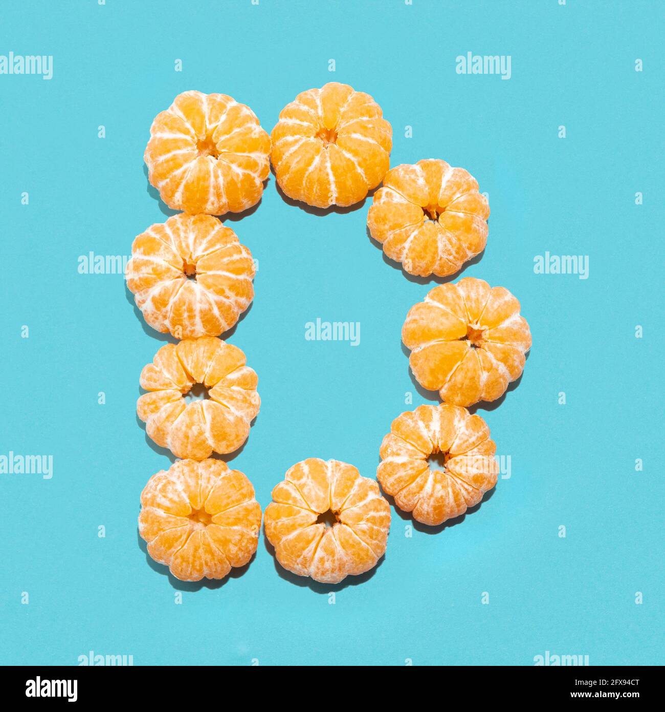 Mise en page créative de la lettre D de mandarines pelées sur fond bleu. Mise à plat. Banque D'Images