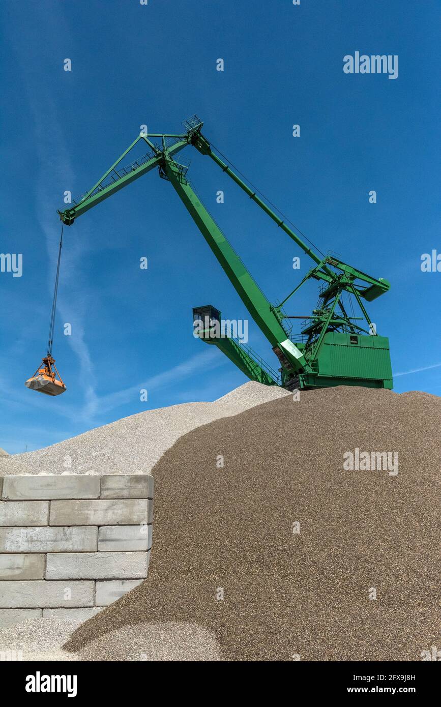 Une grue verte verse du sable et du gravier sur une colline Banque D'Images