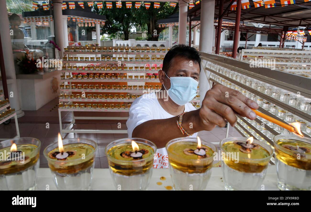 Kuala Lumpur, Malaisie. 26 mai 2021. Un dévot portant un masque allume une lampe à huile dans un temple bouddhiste vide pendant la fête du Wesak. La journée du Wesak, commémore la naissance, l'illumination et le décès du Bouddha Gautama, célébré par les bouddhistes du monde entier. La Malaisie a adopté une nouvelle façon de célébrer le Wesak Day avec l'application de l'ordre de contrôle des mouvements, toutes les réunions sociales et religieuses sont strictement interdites. (Photo de Wong Fok Loy/SOPA Images/Sipa USA) Credit: SIPA USA/Alay Live News Banque D'Images