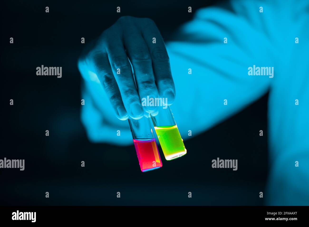 Flacons de verre d'échantillon organique conservés par une femme scientifique dans un laboratoire - radioactif - fluorescence. Un arrière-plan noir d'espace de copie. Bio médicinal ch Banque D'Images