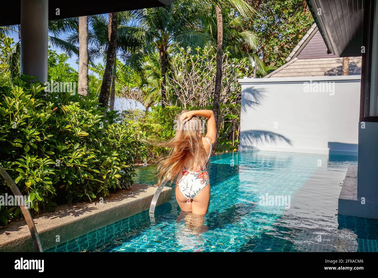 Vue arrière de la femme de voyage dans les maillots de bain dans la piscine Sur Villa de luxe Banque D'Images