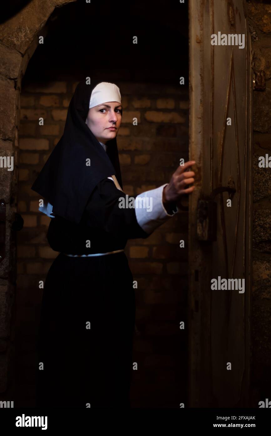 La jeune nonne passe la porte dans le vieux monastère Banque D'Images