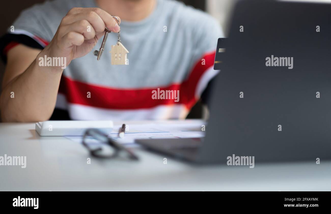 Agent immobilier tenant la clé de maison sur la table avec des dessins de maison document, calculatrice, modèle maison.concept pour l'immobilier. Banque D'Images