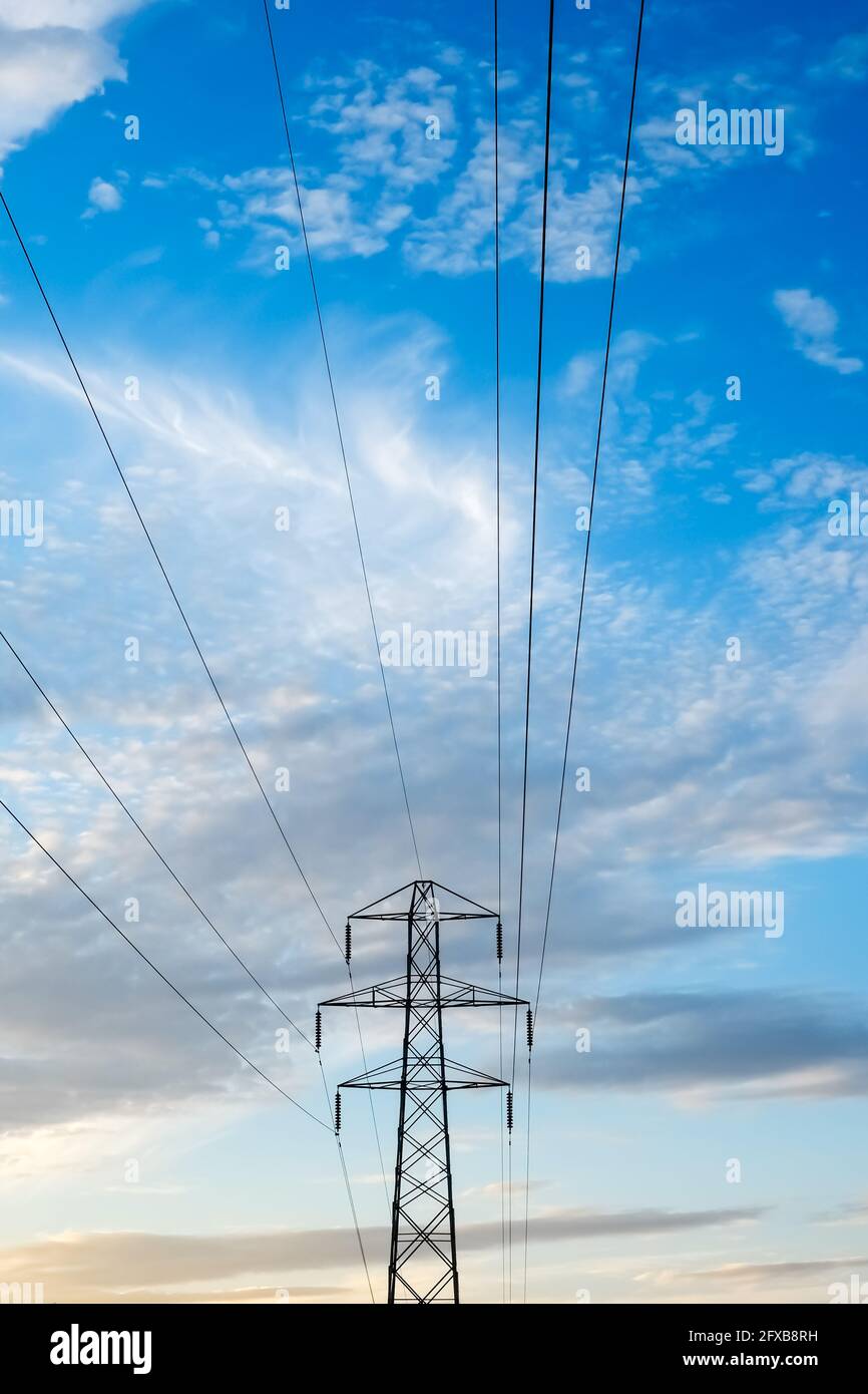 Pylône d'électricité et câbles contre un bleu nuageux et lumineux sky fournit de l'électricité domestique aux maisons pour les besoins en énergie verte Banque D'Images