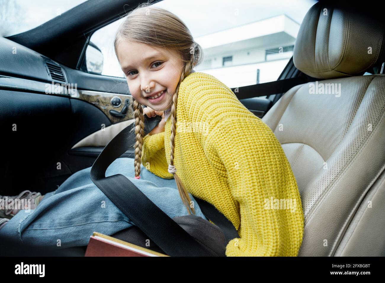 Jolie fille souriante portant des tresses assises en voiture Banque D'Images