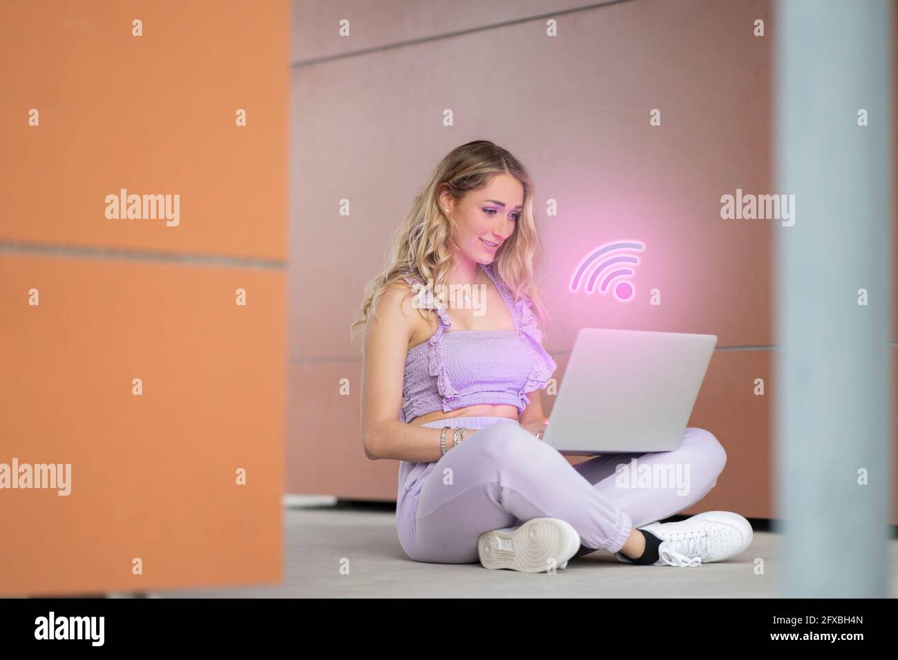 Belle femme utilisant un ordinateur portable avec logo WIFI généré numériquement Banque D'Images