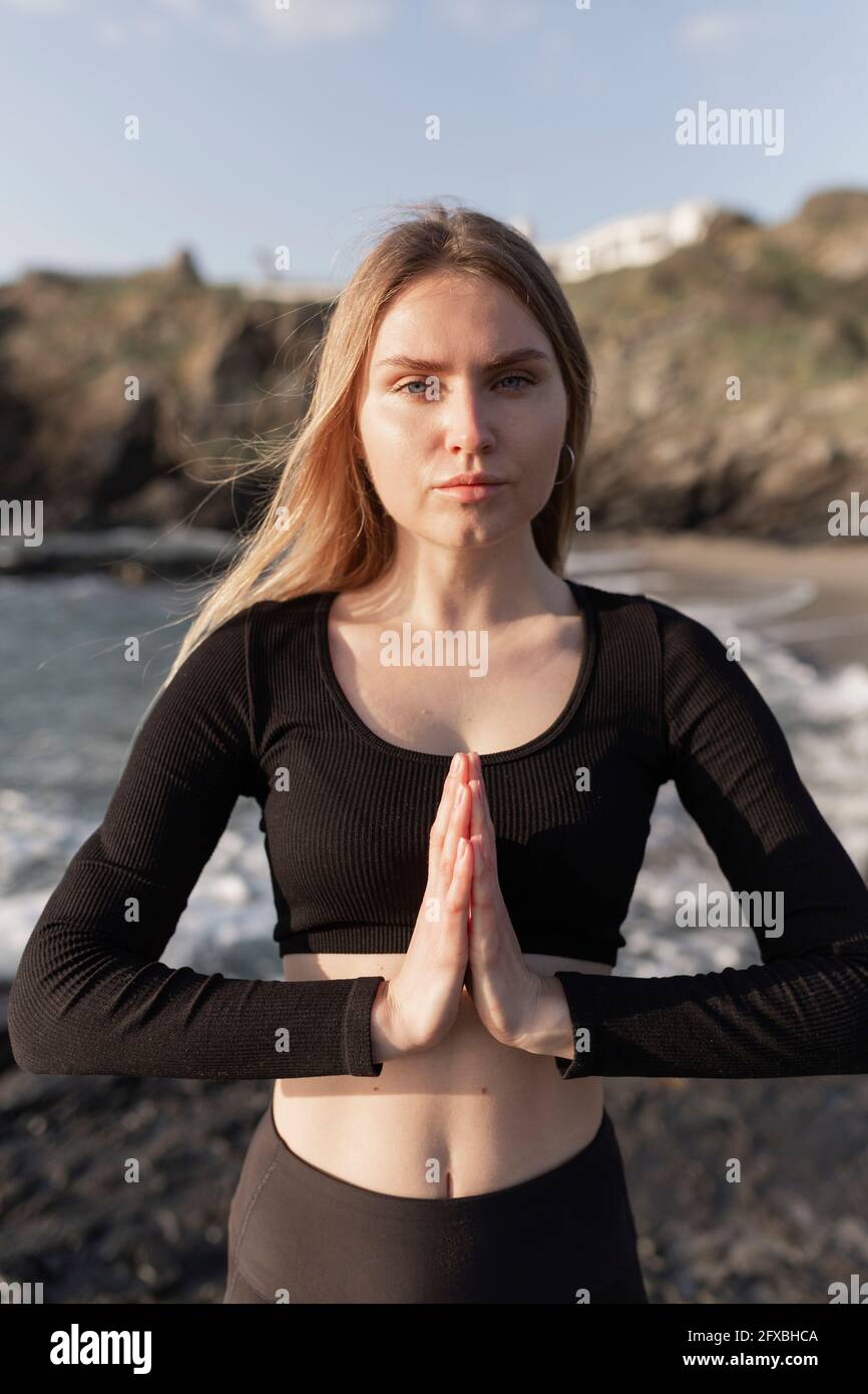 Belle femme debout avec les mains jointes à la plage Banque D'Images